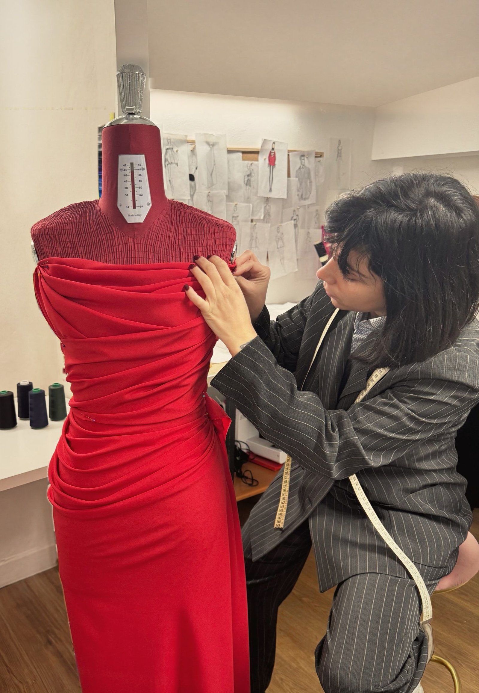 Drappeggio di un abito rosso sul manichino, in atelier